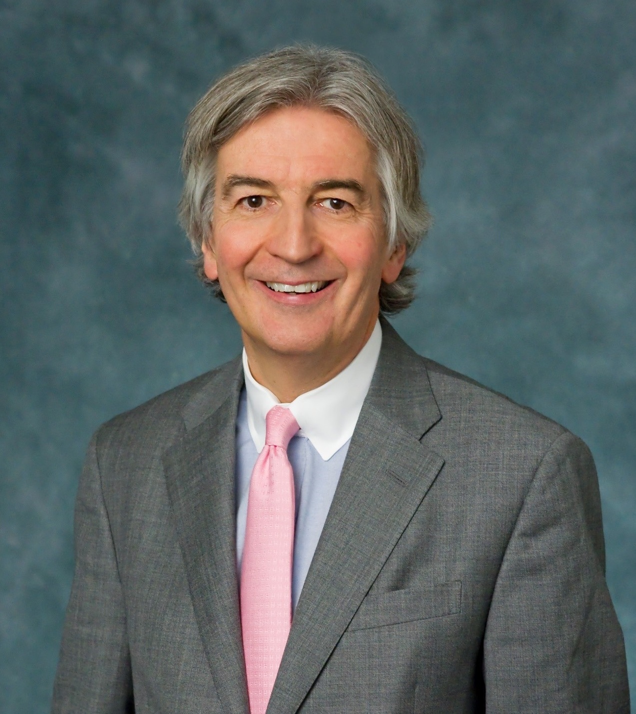 A person wearing a suit and tie smiling at the camera  Description automatically generated